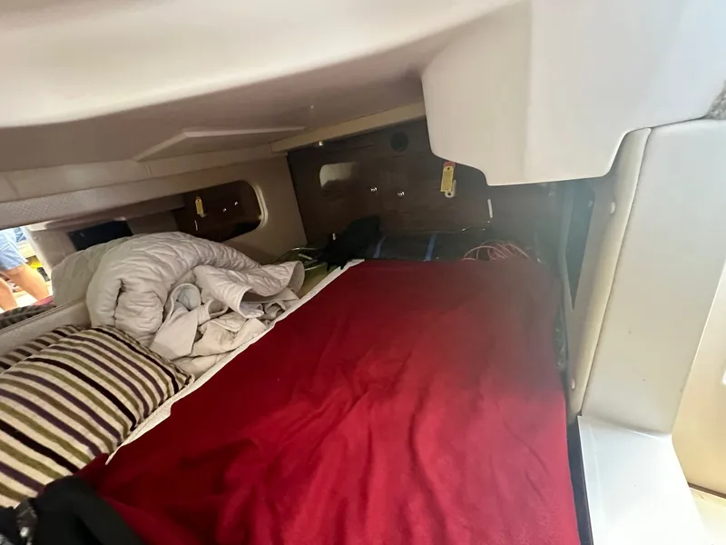 Slide: The Image of The cabin of the 2014 Regal 30 Express features a cozy bed with red and striped pillows. - 28