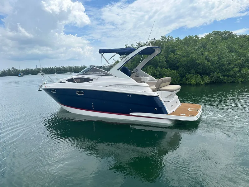 Slide: The Image of A 2014 Regal 30 Express boat on calm water, surrounded by lush greenery. - 1