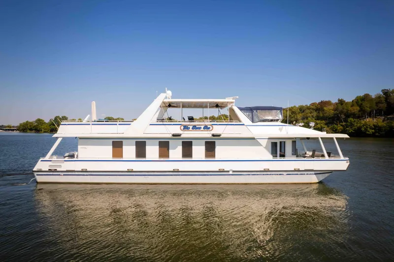 The Image of 2004 Stardust Cruisers Widebody 72x18 houseboat cruising on a calm lake under clear skies. - 1