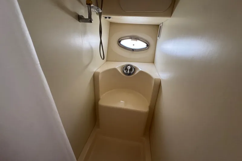 Slide: The Image of Shower area inside 2005 Silverton 34 Convertible boat, featuring a compact design and porthole window. - 43