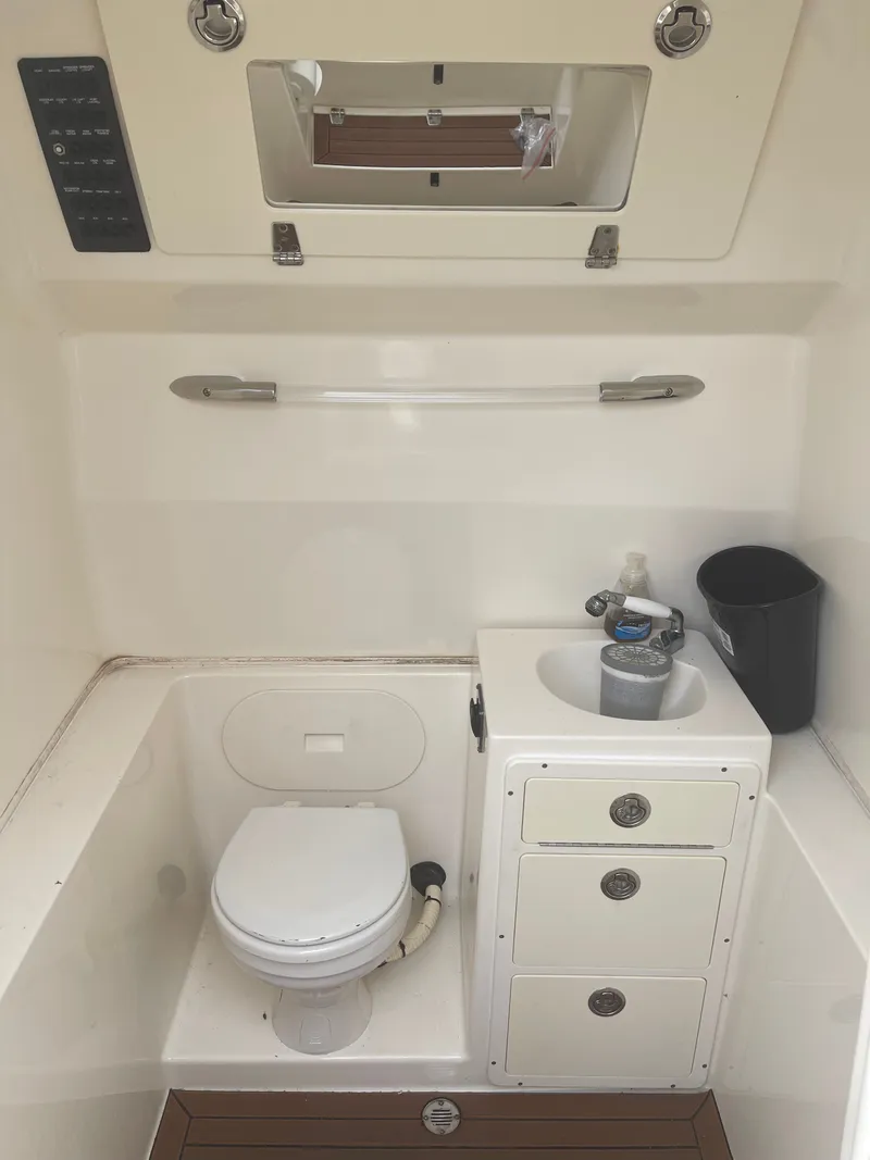 Slide: The Image of Interior of a 2016 Cobia 296 Center Console featuring a toilet and sink. - 27