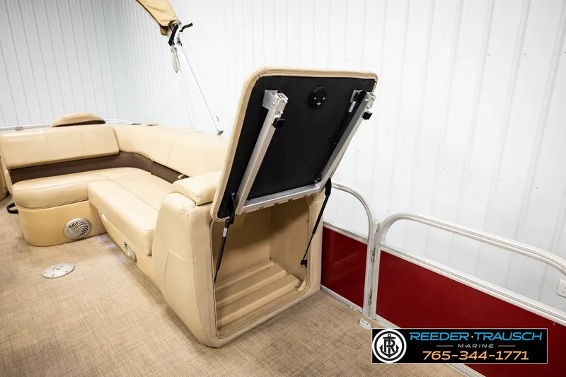 Slide: The Image of 2019 SUNTRACKER 20 DLX pontoon boat interior with beige seating and storage compartment open. - 24
