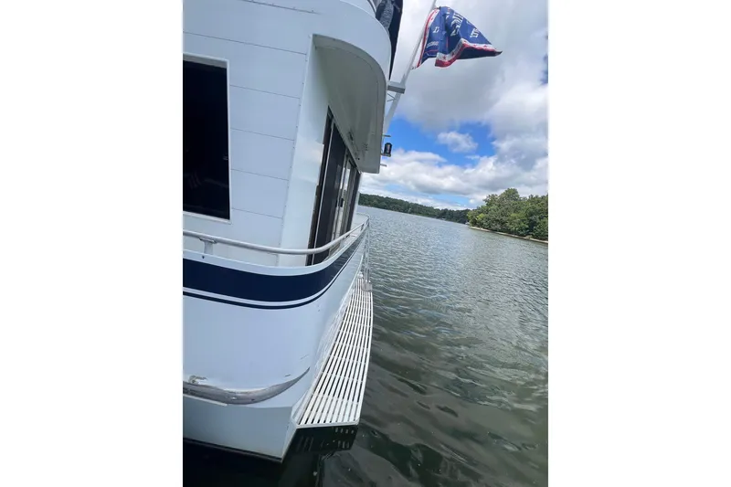 Slide: The Image of 1982 Pluckebaum Coastal Cruiser on serene lake with blue sky and trees. - 4