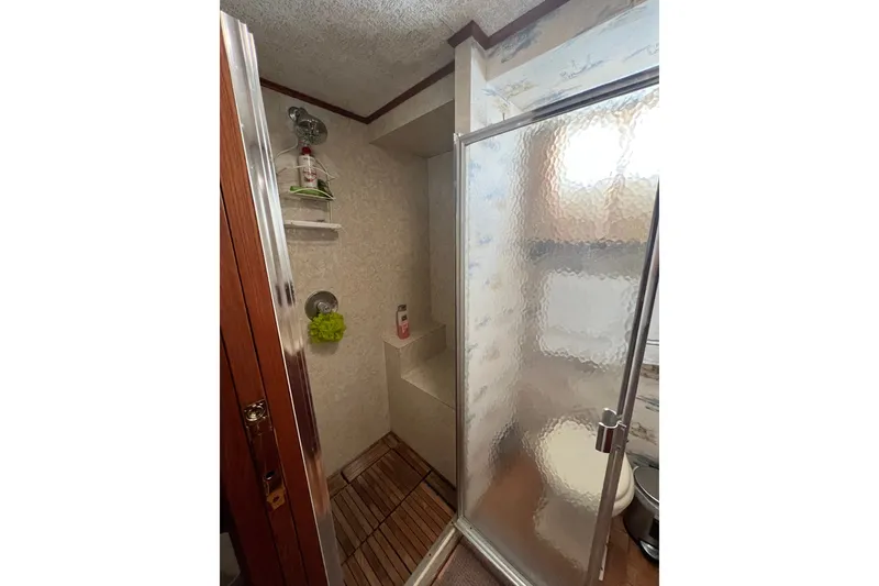Slide: The Image of 1982 Pluckebaum Coastal Cruiser bathroom with shower, wooden floor, and frosted glass door. - 33
