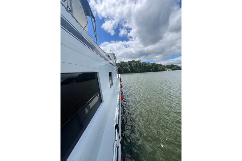 Slide: The Image of 1982 Pluckebaum Coastal Cruiser on serene lake under partly cloudy sky. - 6