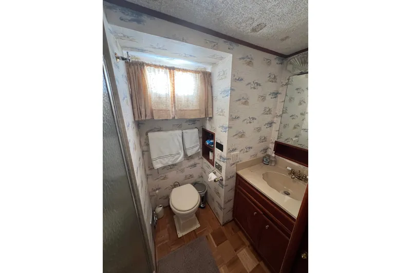 Slide: The Image of 1982 Pluckebaum Coastal Cruiser bathroom with nautical wallpaper, sink, and toilet. - 32