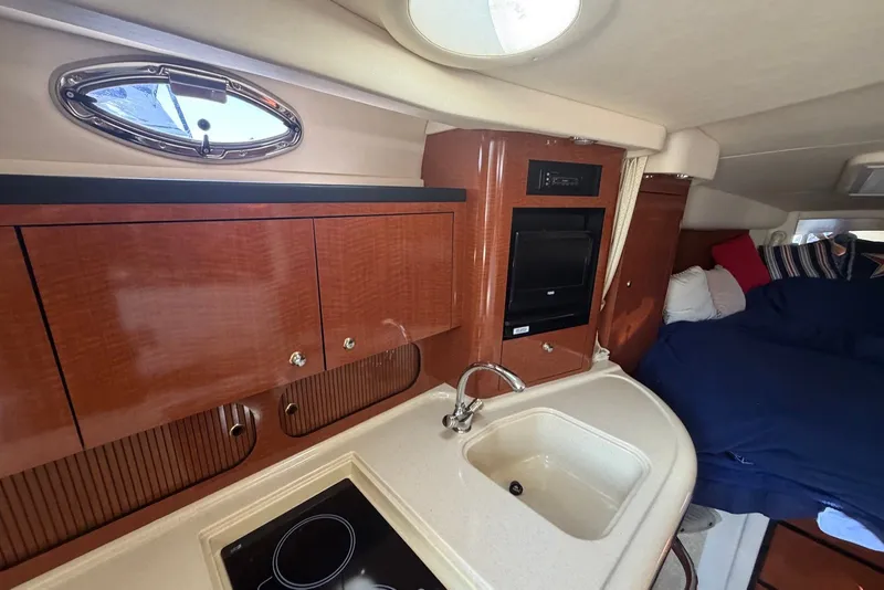Slide: The Image of 2004 Sea Ray 340 Sundancer cabin interior with kitchenette and cozy sleeping area. - 14