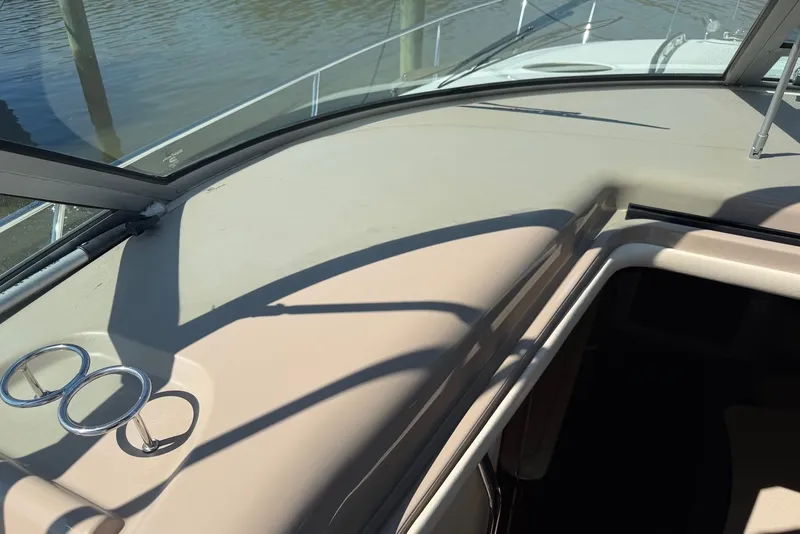 Slide: The Image of 2004 Sea Ray 340 Sundancer boat interior with windshield and cup holders, docked by water. - 11