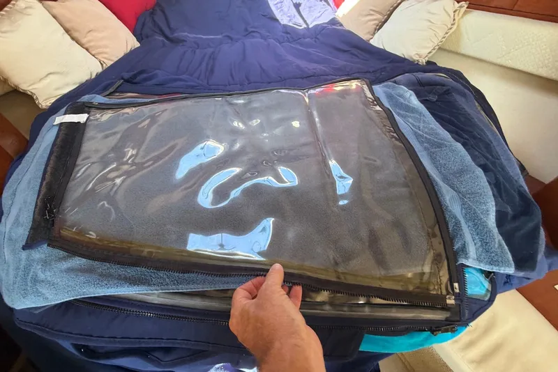 Slide: The Image of Hand holding a clear plastic cover on a bed inside a 2004 Sea Ray 340 Sundancer. - 34