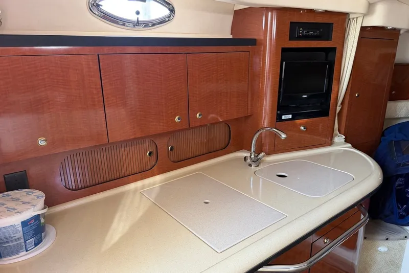 Slide: The Image of 2004 Sea Ray 340 Sundancer cabin kitchen with wood cabinets and sink. - 17