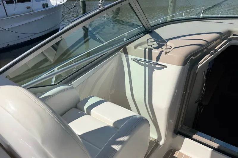Slide: The Image of 2004 Sea Ray 340 Sundancer cockpit with white seating and cup holders, docked by the water. - 10