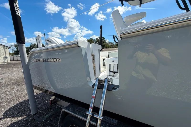 Slide: The Image of 2023 Sportsman Heritage 261 Center Console boat with ladder, parked outdoors under blue sky. - 8