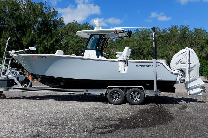 The Image of 2023 Sportsman Heritage 261 Center Console boat on trailer, parked outdoors. - 1