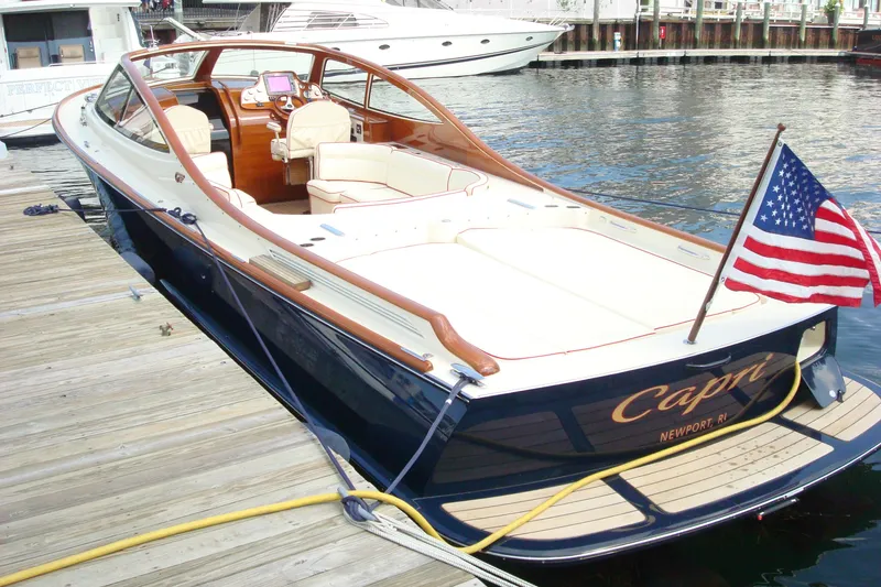 Slide: The Image of 2008 Hinckley Talaria 38R Convertible yacht docked, featuring elegant design and American flag. - 10