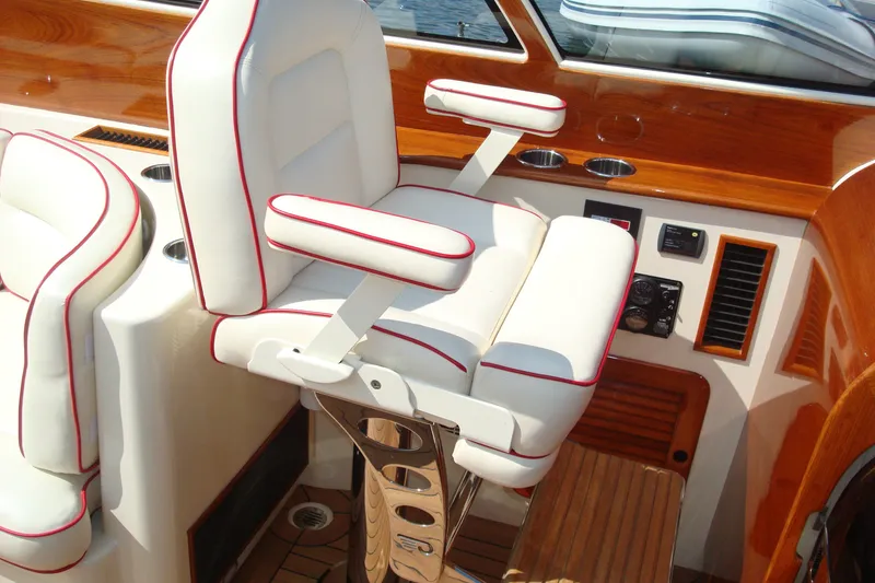 Slide: The Image of Luxury helm seat on 2008 Hinckley Talaria 38R Convertible yacht with white upholstery and red trim. - 2