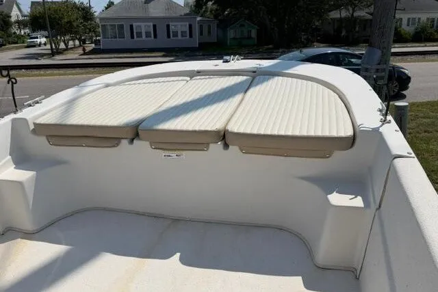 Slide: The Image of 2017 Carolina Skiff 238 DLV boat with cushioned seating, parked in a residential area. - 11