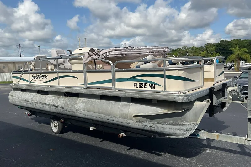 Slide: The Image of 2004 Sweetwater Challenger 200 FC pontoon boat on trailer under cloudy sky. - 2
