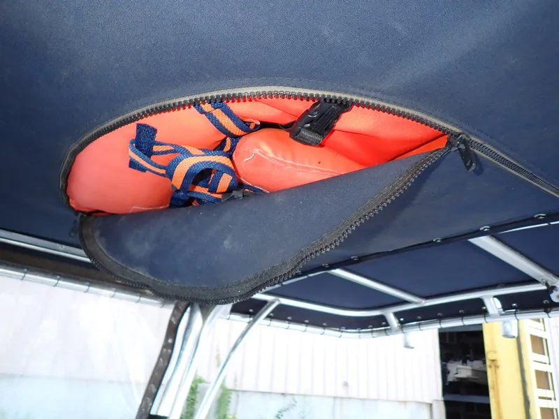Slide: The Image of An orange flotation device is stored in a zippered compartment on a boat's roof. - 22