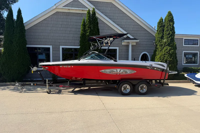The Image of 2005 Correct Craft Air Nautique SV211 Team Edition boat on trailer, parked outside a building. - 1