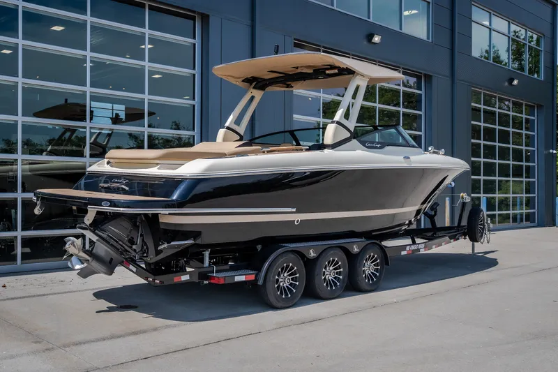 Slide: The Image of 2026 Chris-Craft Sportster 28 boat on trailer, parked outside modern building. - 2