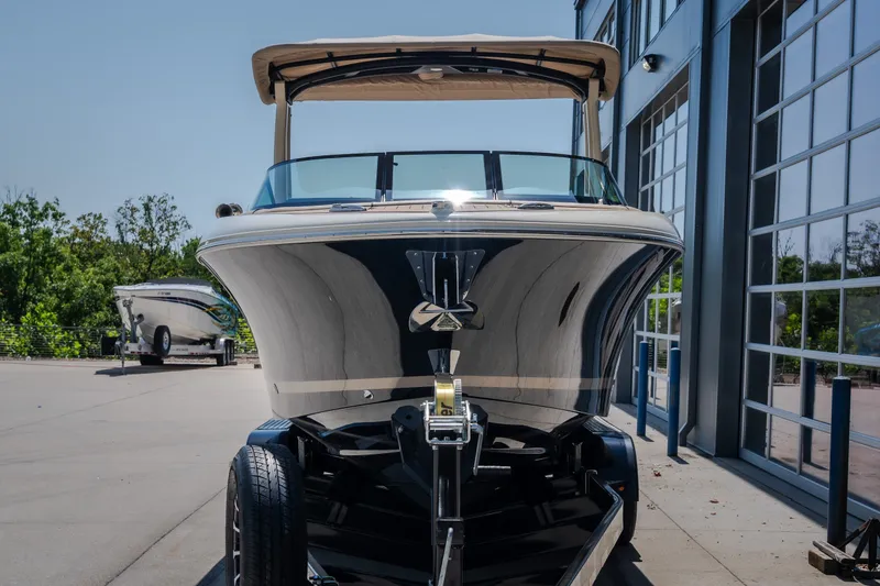 Slide: The Image of 2026 Chris-Craft Sportster 28 boat on trailer, parked outdoors near a modern building. - 3