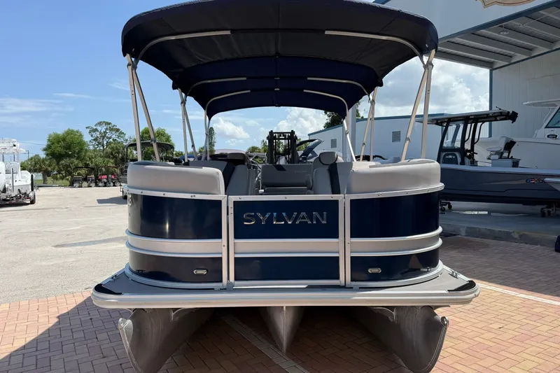 Slide: The Image of 2022 Sylvan L3 DLZ pontoon boat with canopy, parked outdoors on a sunny day. - 2