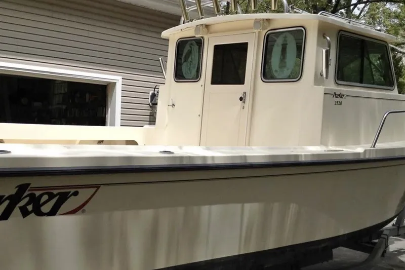 Slide: The Image of 2004 Parker 2520 Modified Vee Sport Cabin boat docked near a garage. - 6