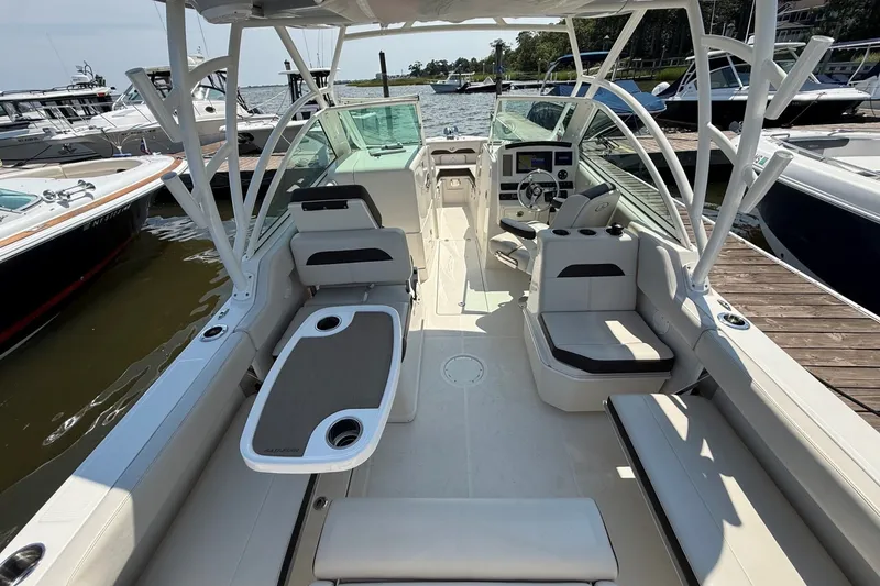 Slide: The Image of 2022 Sailfish 245 DC boat interior with seating, table, and steering console at dock. - 8
