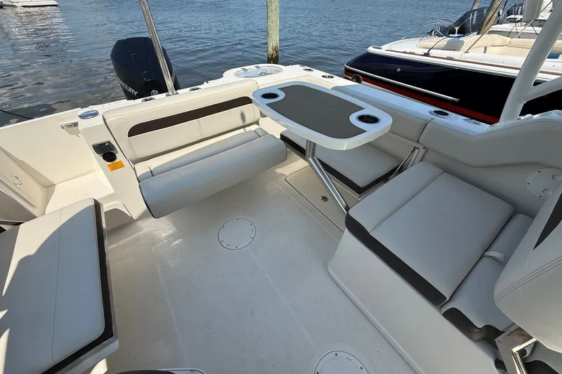 Slide: The Image of 2022 Sailfish 245 DC boat interior with seating and table, docked by the water. - 7