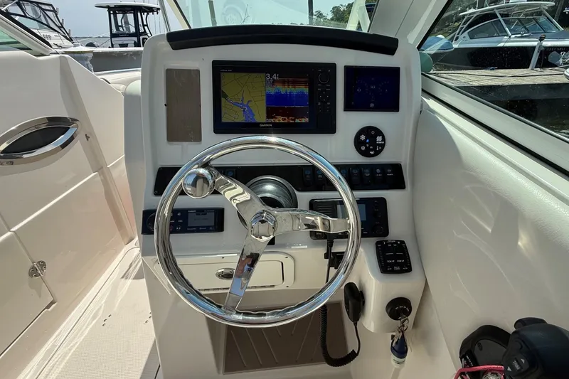 Slide: The Image of 2022 Sailfish 245 DC boat dashboard with steering wheel and navigation controls. - 16