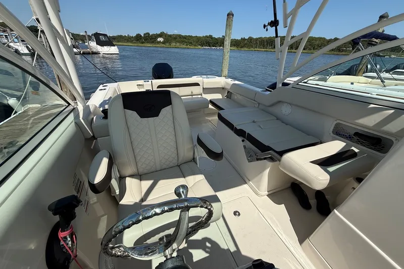 Slide: The Image of 2022 Sailfish 245 DC boat interior with luxurious seating and steering wheel, docked by the water. - 11