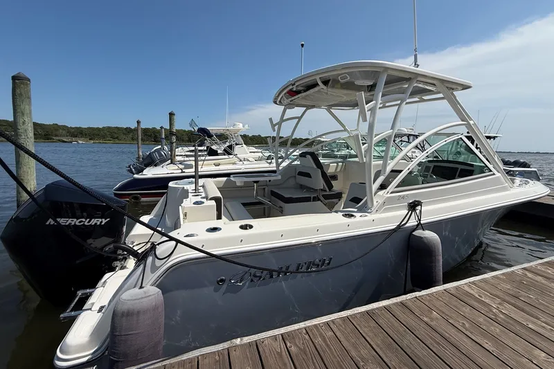 Slide: The Image of 2022 Sailfish 245 DC boat docked, featuring a Mercury engine and sleek design. - 2