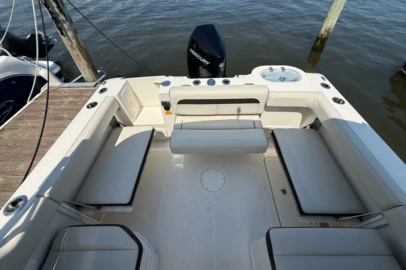 Slide: The Image of 2022 Sailfish 245 DC boat interior with seating and outboard motor, docked by the water. - 6