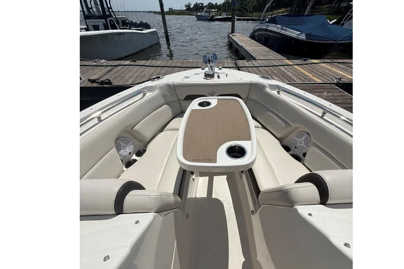 Slide: The Image of 2022 Sailfish 245 DC boat interior with seating and table, docked by the water. - 21