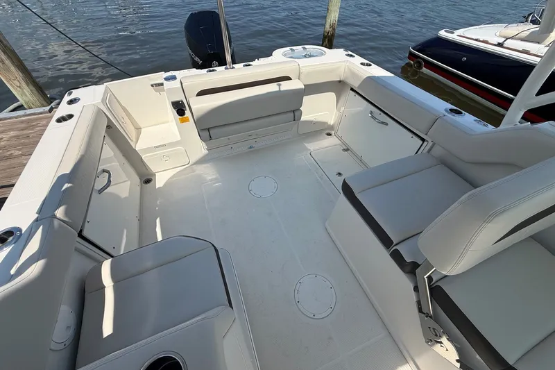 Slide: The Image of 2022 Sailfish 245 DC boat interior with spacious seating and storage, docked by the water. - 5