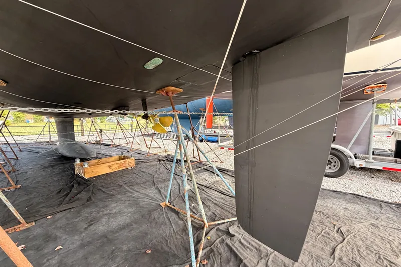 Slide: The Image of Underneath view of a 2016 Jeanneau 64 sailboat on stands, showing keel and rudder. - 50