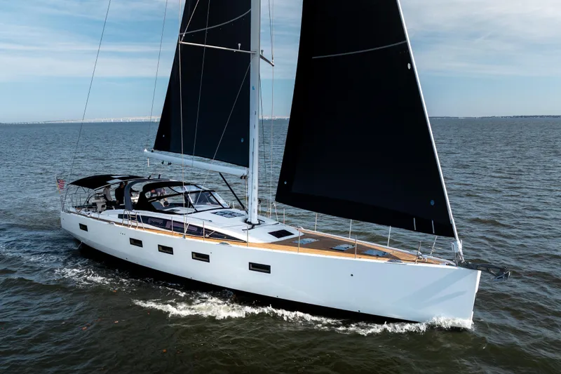 The Image of 2016 Jeanneau 64 sailing yacht with sleek black sails on open water. - 0