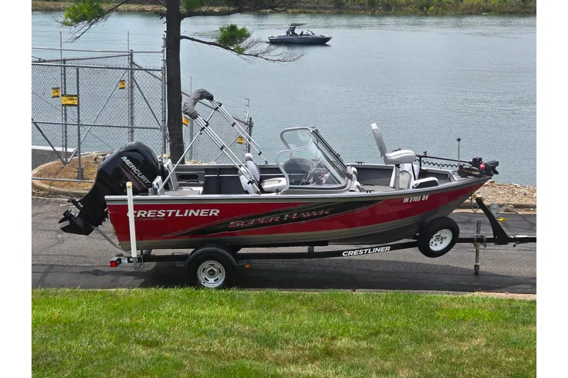 The Image of 2014 Crestliner 1650 Super Hawk boat on trailer by a lake. - 0