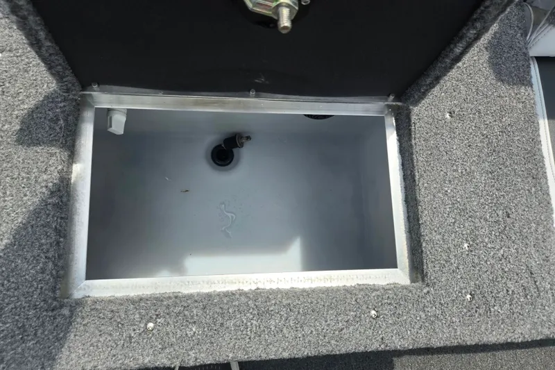 Slide: The Image of Open storage compartment in 2014 Crestliner 1650 Super Hawk boat, featuring gray carpeted interior. - 26