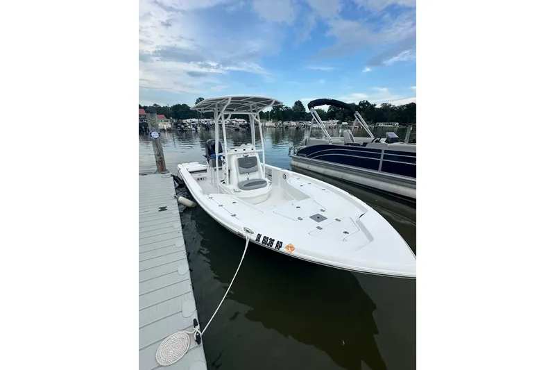 The Image of 2025 NauticStar 214 Shallow Bay boat docked on calm water, clear sky background. - 0