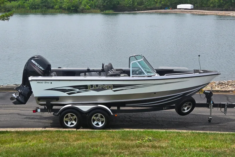 The Image of 2014 Lund 1900 Tyee boat on trailer by a lake. - 0