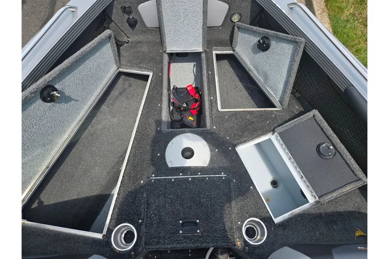 Slide: The Image of 2014 Lund 1900 Tyee boat interior with open storage compartments and carpeted flooring. - 21