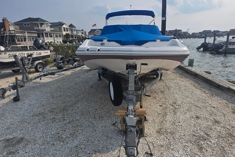 Slide: The Image of 2014 Hurricane SunDeck 187 OB boat on trailer, dockside with waterfront homes in background. - 7