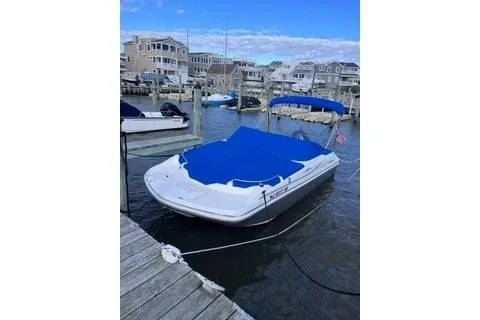 Slide: The Image of 2014 Hurricane SunDeck 187 OB boat docked with blue cover in a marina setting. - 1