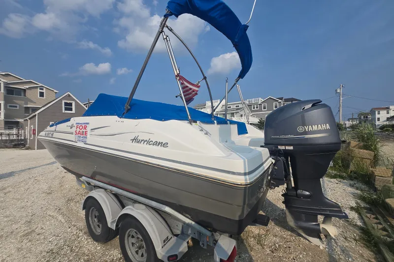 Slide: The Image of 2014 Hurricane SunDeck 187 OB boat for sale with Yamaha outboard motor, parked on trailer. - 2