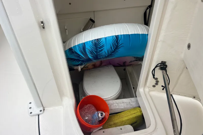 Slide: The Image of 2024 Robalo 266 Cayman boat interior with storage items and marine toilet. - 16