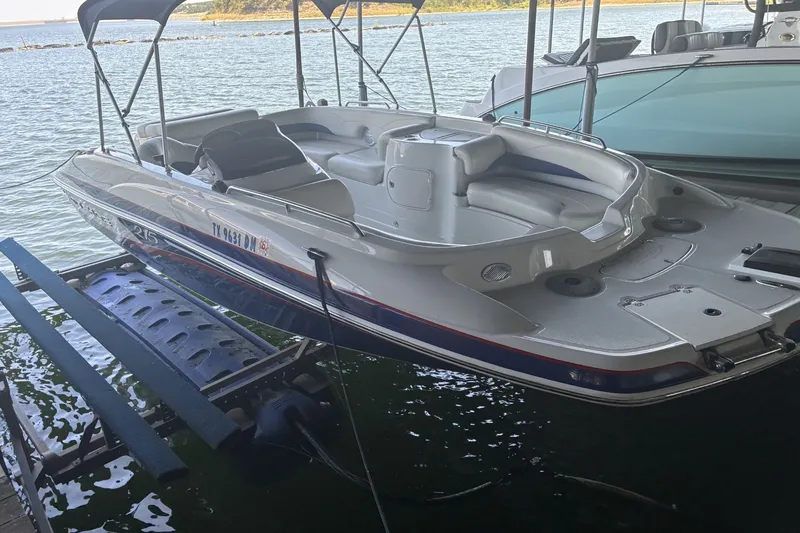 The Image of 2015 Tahoe 215xi I/O boat docked on a lift by the water. - 0
