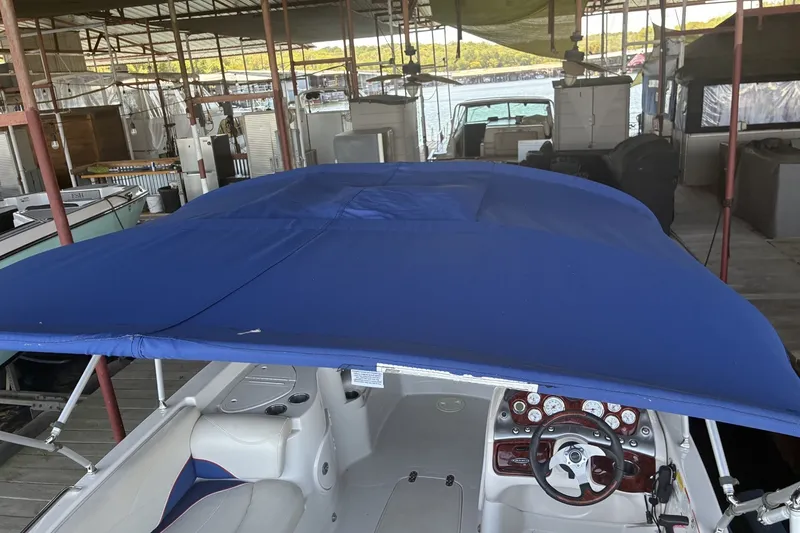 Slide: The Image of 2015 Tahoe 215xi I/O boat with blue canopy in a marina dock setting. - 15