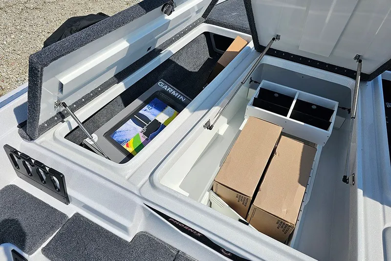 Slide: The Image of Open storage compartments in a 2027 Phoenix 921 Elite X boat, featuring a Garmin device. - 26