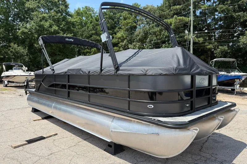 Slide: The Image of 2026 Bentley Pontoons Legacy 243 Navigator, sleek black design, covered, parked outdoors. - 16
